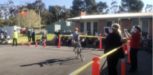 A cyclist waves to residents.