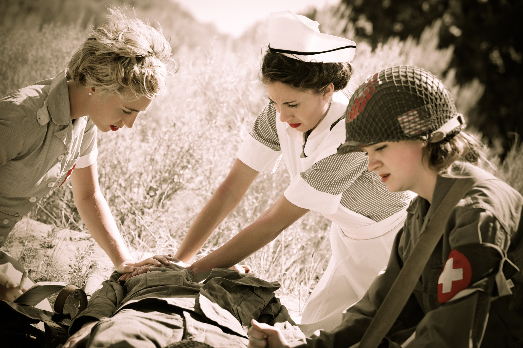 Female nurses & medic assisting wounded soldier in field