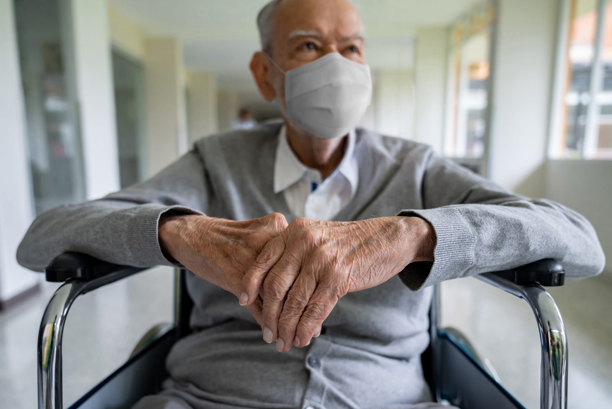 Senior adult in a wheelchair at the hospital wearing a facemask