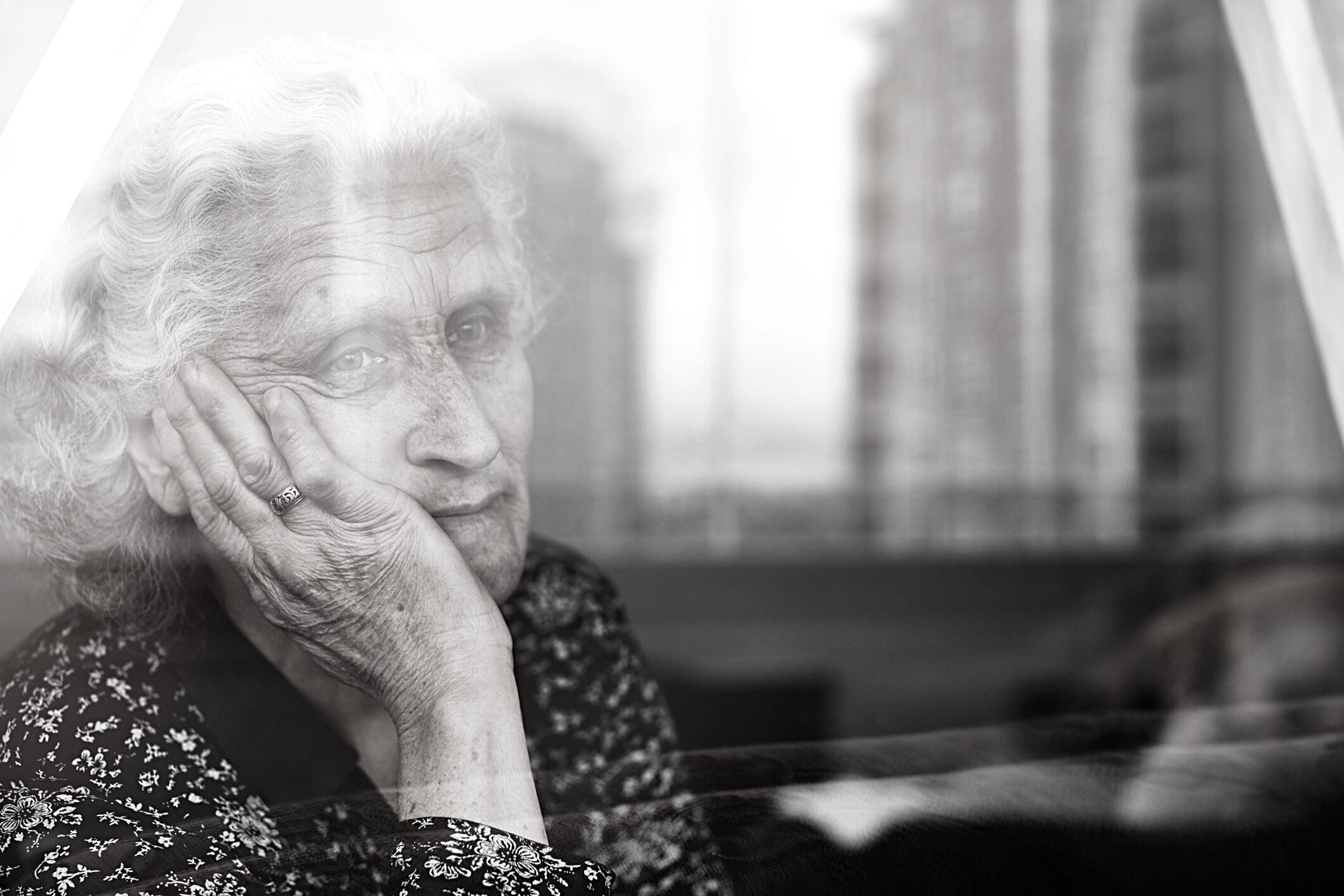 Lonely old woman looking out window