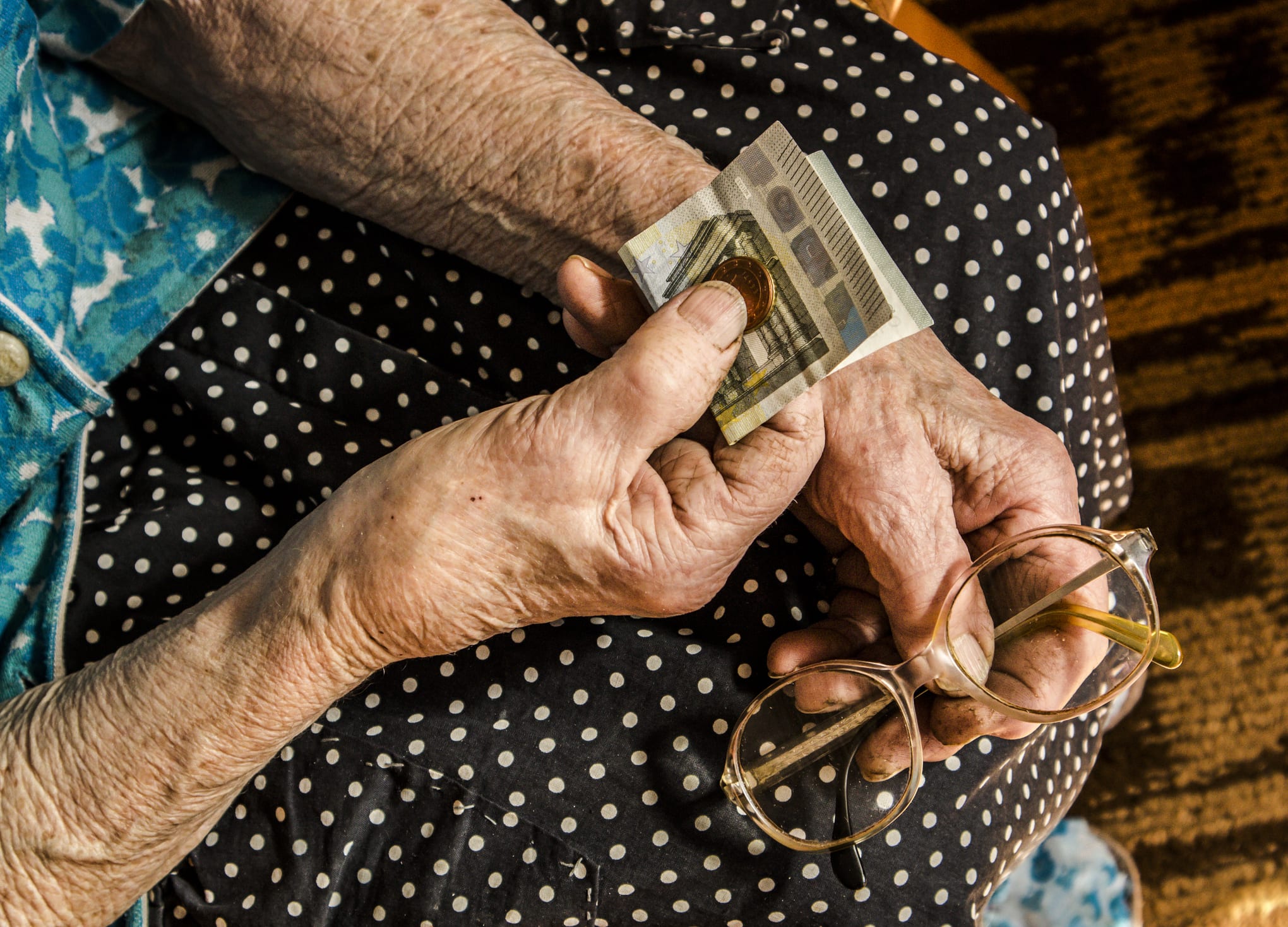 Hard working retired old woman holding money euros in her wrinkled hands.