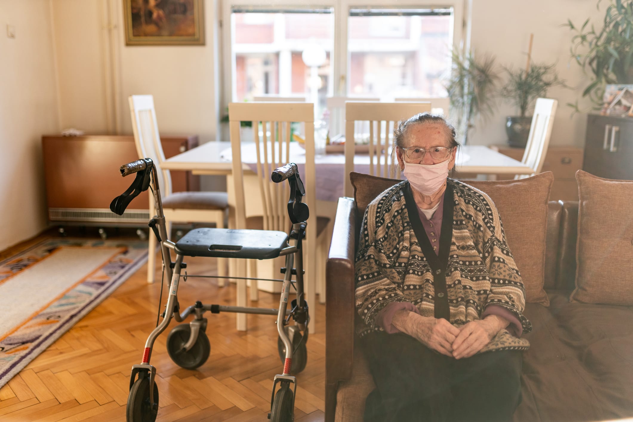 Senior lady with a rollator walking in house during coronavirus home quarantine