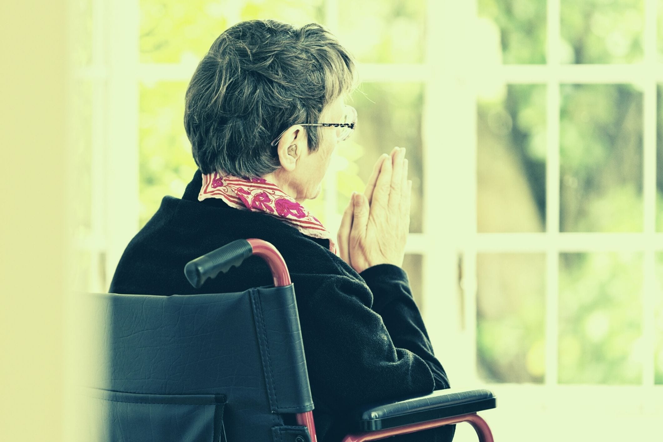 Elderly woman praying in wheelchair