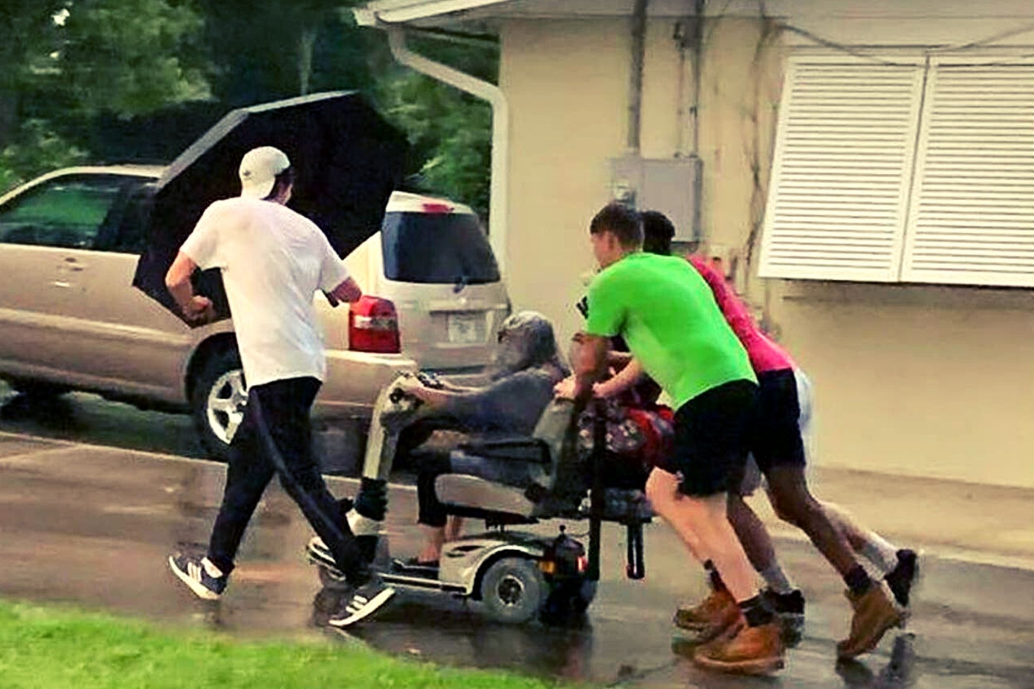 Four young men push elderly woman’s broken scooter home in the pouring rain