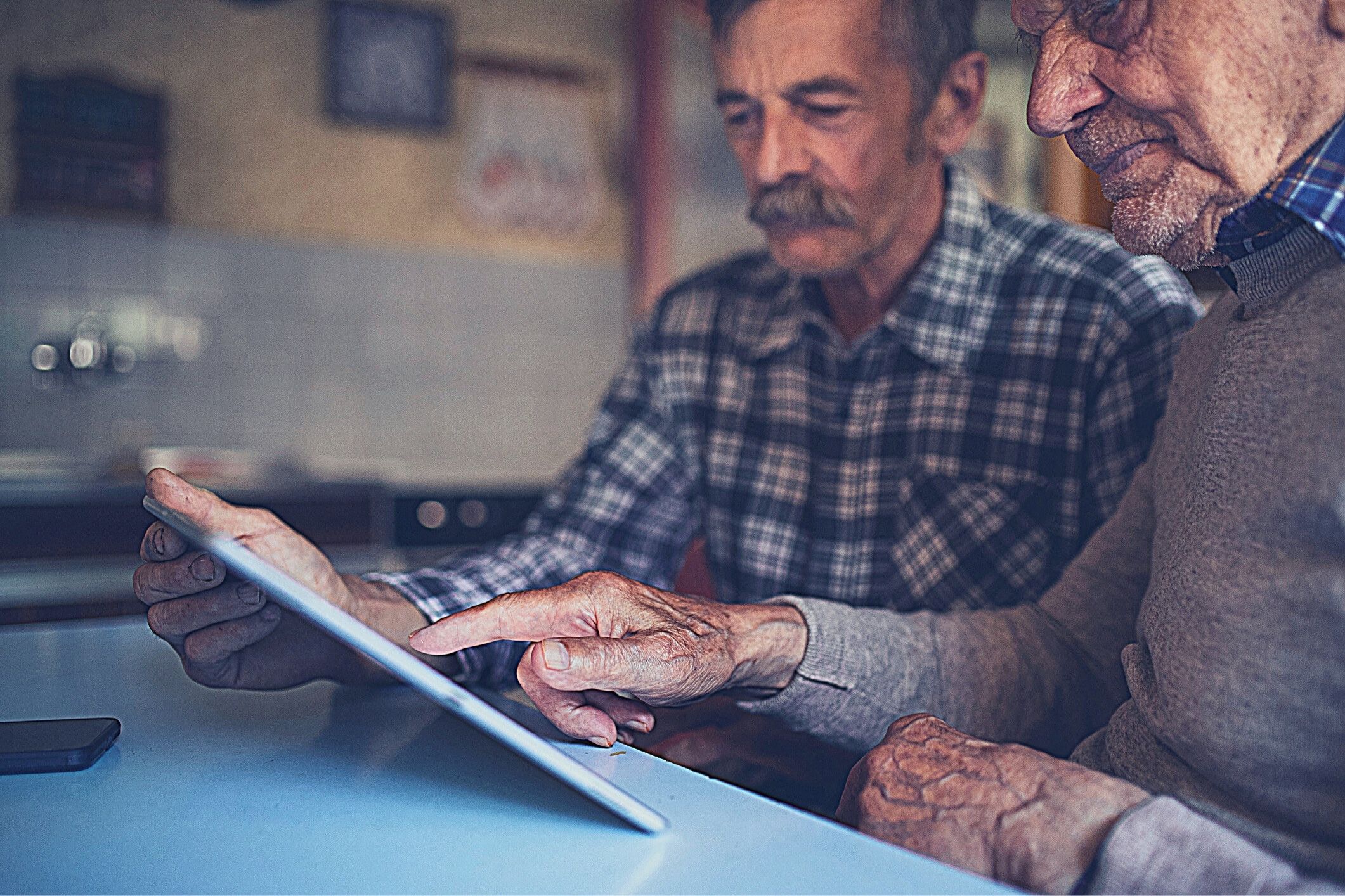 Two older men using tablet