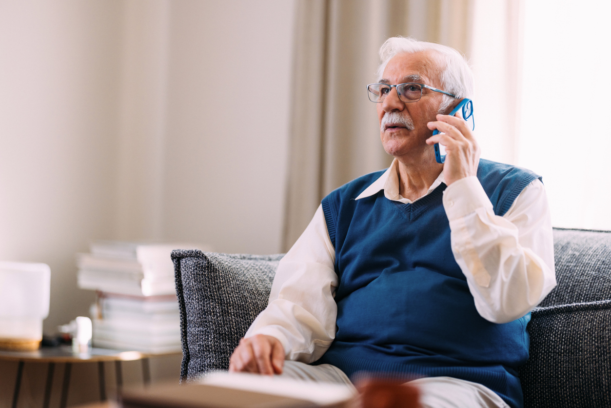 Elderly Man Engaged in Phone Conversation Sitting at Home